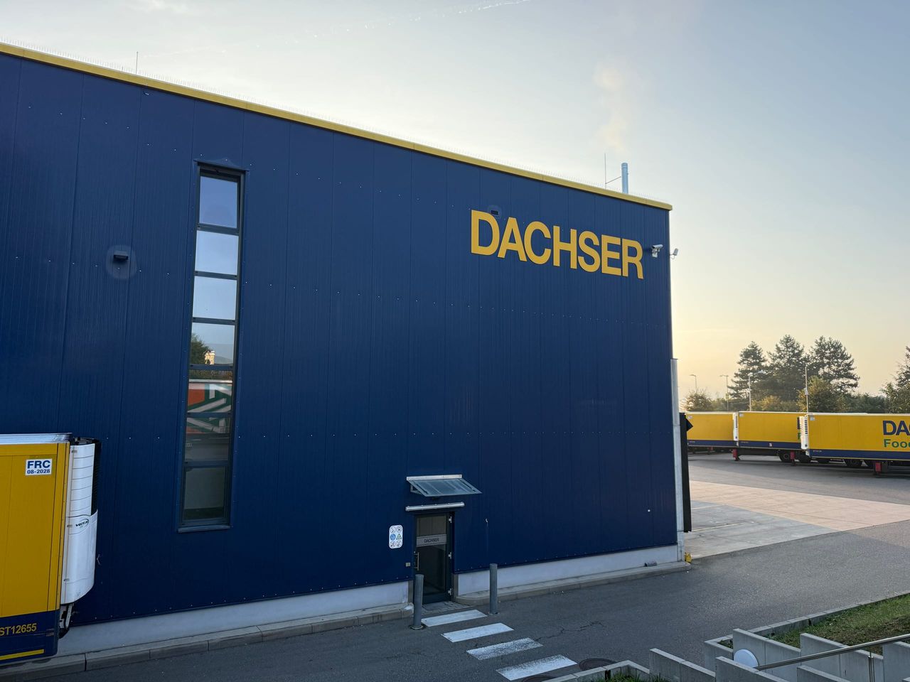 Dunkelblaue Gebäudeecke des DACHSER Logistikzentrums mit Logo, Fenstern und Außentür