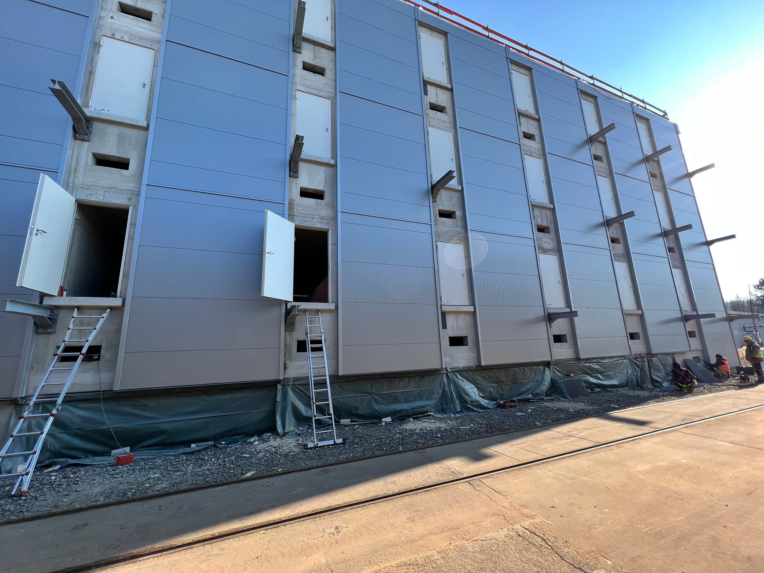 Fassade des neuen Chemielagers der Friedrich Scharr KG mit mehreren geöffneten Außentüren während der Montage